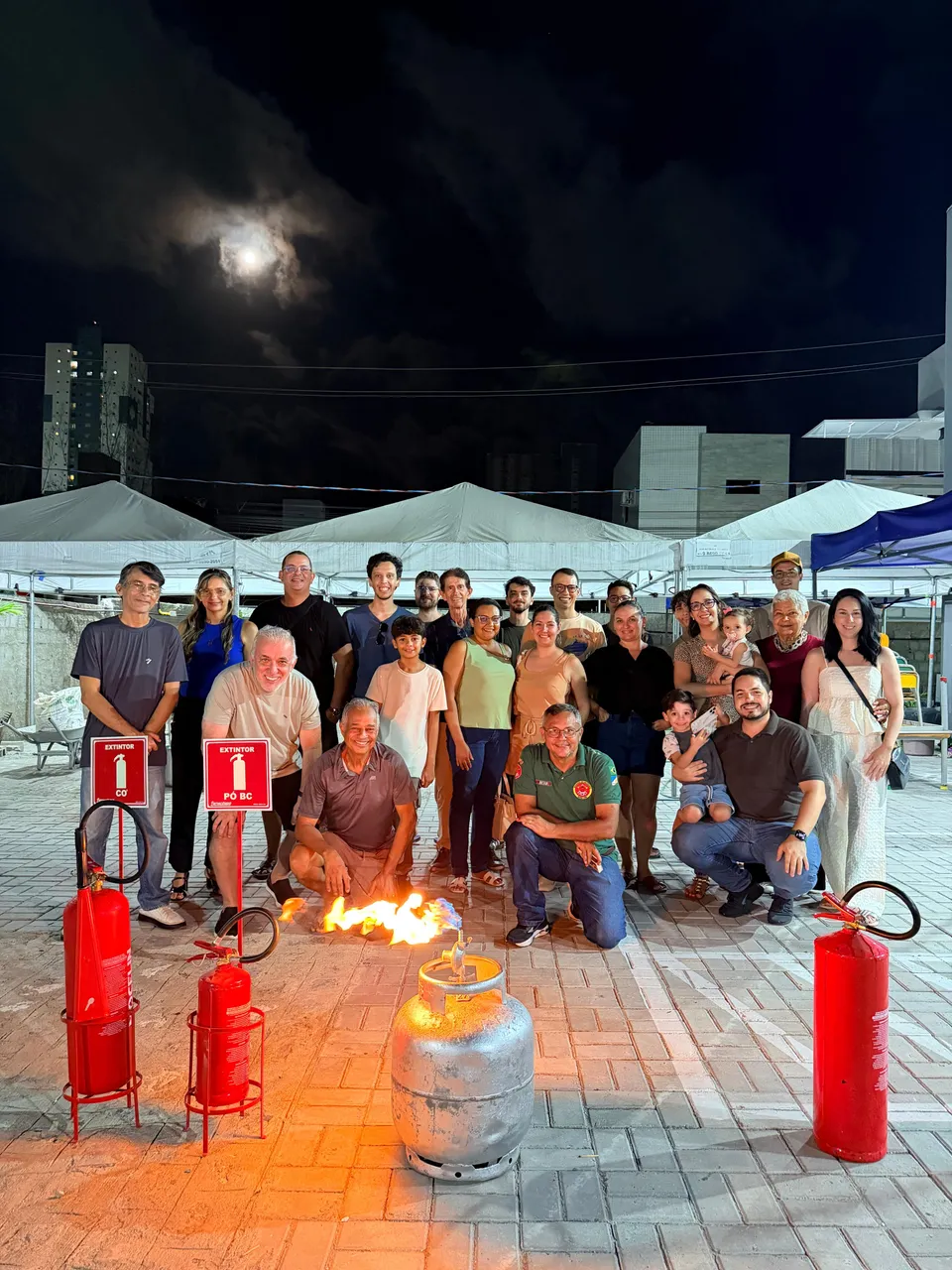 Turma ao final de um treinamento da Bradotec, reunida atrás de uma queima controlada, com extintores de CO2 e de pó BC em primeiro plano